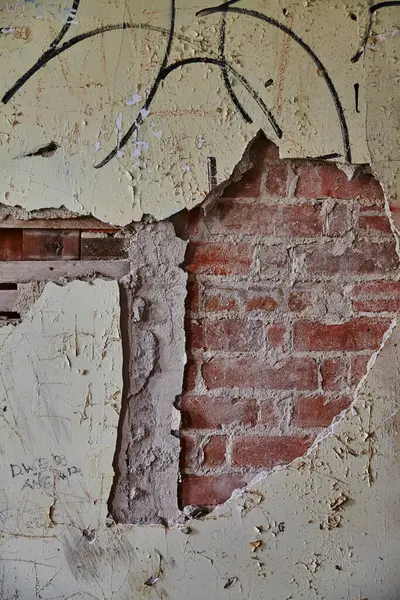 Close-up of a decaying urban wall with graffiti over red bricks, reflecting a sense of abandonment in Lancaster, Ohio.