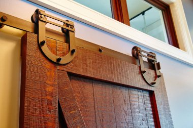 2015 yılında Indiana 'da tasarlanmış, sıcak desenli ahşap ve koyu renkli donanım sergilenen, metal pistte kaygan ahır kapısı.