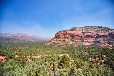 Güneşli gökyüzü altında, doğa ve seyahat temaları için ideal olan Devils Köprüsü, Sedona, Arizona 'da, kırmızı kaya oluşumları ve yeşillik dolu 2016 manzarası