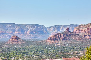 Sedonas 'ın canlı kızıl kaya oluşumları, 2016' da Amerika 'nın güneybatısının huzurlu güzelliğini yakalamak için çölde yuva yapmış küçük bir kasabanın üzerinde..