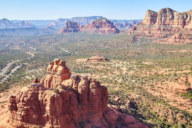 2016 yılında bir helikopterden alınan Sedona, Arizona 'daki kırmızı kayalık çöl manzarasında dolambaçlı yolun gündüz hava görüntüsü