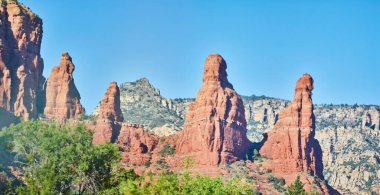 Berrak mavi gökyüzü altındaki yemyeşil yemyeşil kayaların arasında canlı kırmızı kaya oluşumlarının nefes kesici manzarası, Sedona, Arizona, 2016