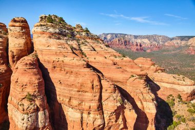 Açık mavi gökyüzü altında, Arizona, Sedona 'da yemyeşil yemyeşil ile çevrili dramatik kırmızı kaya oluşumları, 2016' nın öğle saatlerinde yüksek bir bakış açısıyla ele geçirildi..