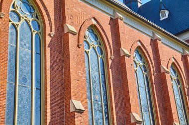 Fort Wayne, Indiana 'daki gotik esinlenilmiş St. Peters Katolik Kilisesi berrak bir gökyüzü altında ışıldayan cam ve kırmızı tuğlalarla vurgulanıyor.