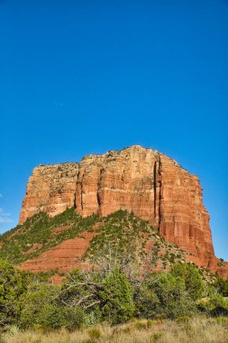Arizonas Sedona Çölü 'ndeki görkemli Kızıl Kaya oluşumu - Berrak mavi gökyüzü altında canlı demir oksit renkleri ve dayanıklı yerel yeşillikler