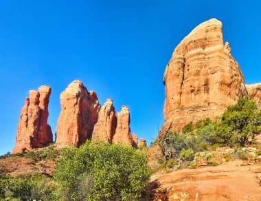 Sedona, Arizona, 2016 kurak manzarasında kırmızı kumtaşı oluşumlarının panoramik görüntüsü. Açık mavi gökyüzünün altında canlı bir doğal güzellik gösterisi..