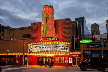 Canlı Devlet Tiyatrosu afişi Ann Arbor şehir merkezinde alacakaranlıkta ışıldıyor, modern şehir manzarasının karşısında klasik bir cazibe var.