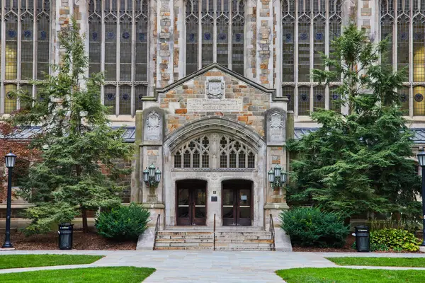 Michigan Üniversitesi Hukuk Fakültesi Karmaşık ahşap kapılar, süslü taş kemer yolu ve çevreleyen yeşillik girişi