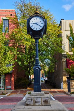 Historic Ypsilanti street clock in Michigan, featuring lush greenery and brick buildings, depicting small-town charm and heritage. clipart