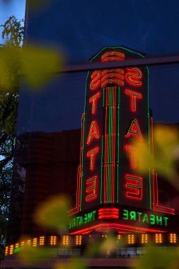 Eyalet Tiyatrosu 'nun parlak ışığı tarihi Ann Arbor, Michigan şehir merkezindeki camlara yansıyor ve gece gökyüzünde parlıyor.