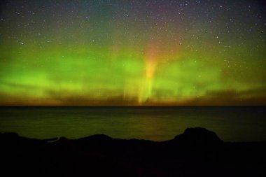 Titrek Aurora Borealis sakin okyanus ve kayalık arazi üzerinde Copper Harbor, Michigan 'da 2017' de büyüleyici bir gece gökyüzü manzarası yarattı..
