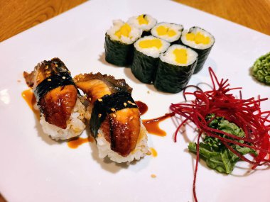 Cilalı yılan balığı nigiri ve tamago maki içeren gurme suşi tabağı, 2023 yılında Fort Wayne 'de lüks bir restoranda wasabi ve doğranmış pancar ile servis ediliyor..