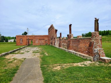 Yıkılmış, parçalı bulutlu bir gökyüzünün altındaki tarihi tuğla binanın gündüz görüntüsü, Vernon Dağı, Ohio, 2023 kırsal kesiminde, zaman geçişini ve kentsel bozulmayı yansıtıyor.
