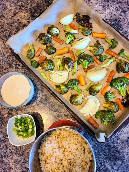 Overhead view of a wholesome home-cooked meal featuring roasted vegetables, fluffy white rice, and fresh garnish prepared in a Fort Wayne kitchen, Indiana, 2023.