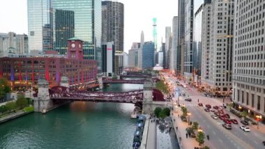 Chicago, Illinois şehir merkezinin hava izleme çekimi, mavi saatte parlayan şehir manzarasına karşı canlı şehir yaşamını sergiliyor, ikonik kanallar ve parlak gökdelenlerle.