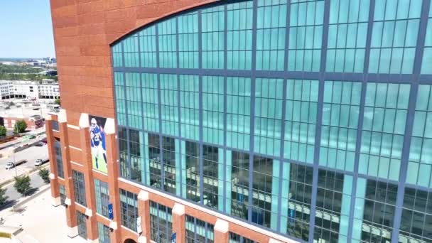 インディアナポリスのルーカス オイル スタジアムの空中ペデスタル ショット 建築の壮大さ 署名された煉瓦工事 活気に満ちた都市背景に対する象徴的な看板の魅惑的な眺め — ストック動画