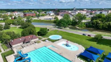 Tuhey Park 'ın, Muncie, Indiana' nın, havuzu, yemyeşil ve şehir manzarasının ortasındaki canlı bir şehir parkını gösteren ileri doğru uçuşu..