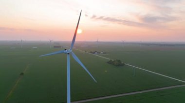 Güneş doğarken Ohios tarım arazisindeki rüzgar türbinlerinin hava görüntüsü kırsal yeşil enerjinin barışçıl gücünü gösteriyor..