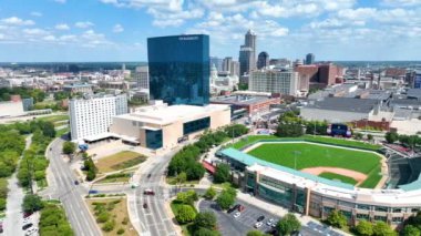 Dinamik Indianapolis 'in Havadan Görünümü: Indy şehir merkezinin geniş bir panoraması, açık mavi gökyüzü altında, Zafer Alanlarının yeşil alanlarını modern mimariye kadar takip ediyor.