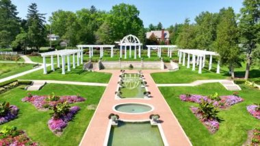 Fort Wayne, Indiana 'da bulunan Lakeside Park' ın Tersten Uçuşu titiz simetrik bahçe tasarımını, su özelliklerinin sükunetini ve canlı bir şekilde yıkanmış davetkar merkezi bir çardağı gözler önüne seriyor.