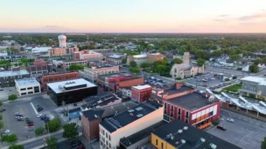 Aerial Pan Shot: Muncie, Indiana şehir merkezinde altın saat banyosu, Delaware İl Mahkemesi binasını, tarihi mimariyi ve kırsal bir zemine karşı hareketli sokakları vurguluyor.