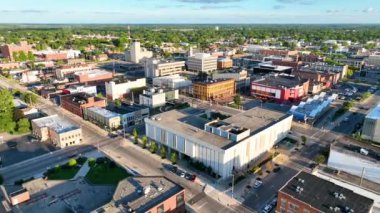 Muncie, Indiana 'nın şehir merkezinden Aerial Fly Over, sıcak öğleden sonra ışıklarıyla yıkanmış aktif bir şehir manzarası sergiliyor. Yeşil alanlar arasında modern ve tarihi mimarinin bir karışımı..