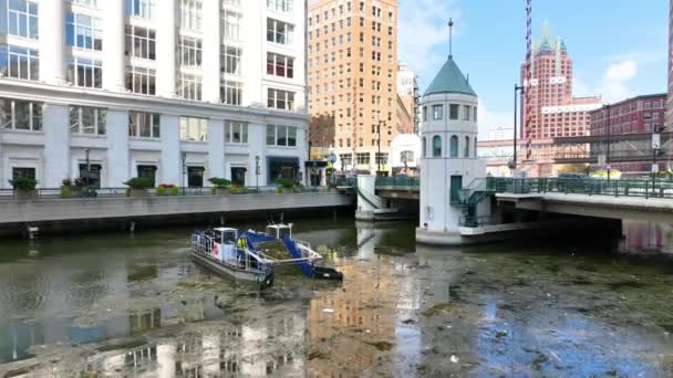 空中飞驰而过的一艘河船勤勉地清扫密尔沃基运河 展示了这座城市的城市建筑和对环境管理的承诺的混合 — 图库视频影像