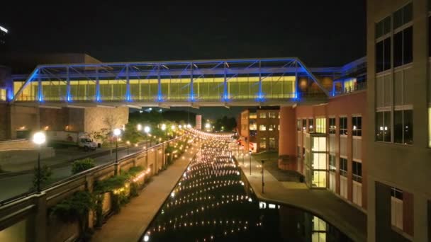 在印第安纳波利斯繁华的市中心 空中飞驰而过 以令人叹为观止 灯火通明的人行天桥和现代光彩夺目的建筑 捕捉着宁静的运河 — 图库视频影像