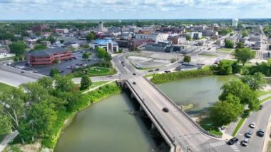 Muncie, Indiana 'dan Aerial Fly, şehir kalp atışlarını ve sakin manzaraları gösteriyor. Video, Beyaz Nehir, önemli bir köprü ve şehir merkezi üzerinde dinamik bir ileri hareket içerir..
