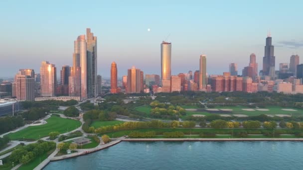 ゴールデンアワーでシカゴのダウンタウンショットを設立 高層ビルの暖かい光を捉え ミシガン湖を穏やかにし 日暮れから夕暮れに移る活気に満ちた緑の空間 — ストック動画