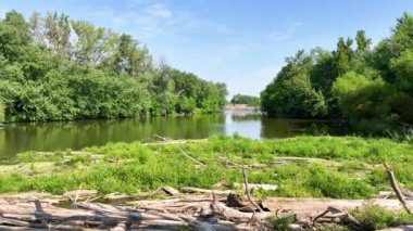Fort Wayne, Indiana 'daki sakin Maumee Nehri Barajı' nın Tersten Uçuşu 'nda el değmemiş doğa ve mimari unsurların parlak gün ışığı altında sakin bir karışımı sergileniyor. İdeal