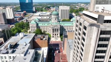 Indianapolis 'teki İndiana Eyalet Binası' nın İleri Uçuşu modern şehir manzarası altında canlı mavi gökyüzü altında tarihsel ihtişamını yakalıyor..