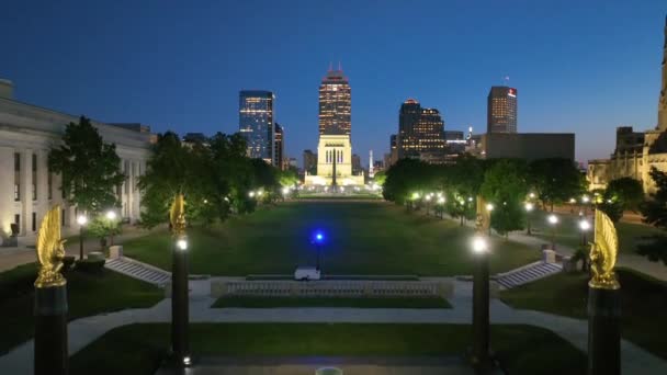夕暮れのインディアナポリスの静かなダウンタウンに向かって空飛ぶ 輝くインディアナ戦争記念館と博物館 黄金の鷲とライトの都市のスカイラインに囲まれた — ストック動画