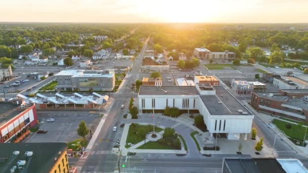 空中追跡ショット 穏やかな街並みの中でデラウェア郡裁判所のビルを特徴とするインディアナ州ミュンシーのダウンタウンのゴールデンアワーが輝く — ストック動画