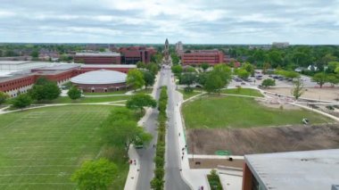 Top State Üniversitesi, Indiana 'daki Aerial Fly Over Forward, kırmızı tuğlalı binalar, hareketli kampüs hayatı ve sakin akademik çevresiyle donatılmış yeşil manzarasını sergiliyor..