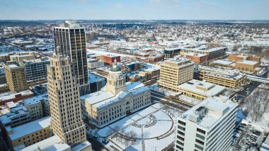 Fort Wayne, Indiana 'da kışlar birbirine dokunur: Tarihi adliye sarayı ve şehir merkezinin kar örtüsü altında karışımını gösteren sakin bir hava manzarası.