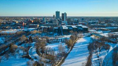 Fort Wayne 'de Kış Şafağı - Kardan öpülmüş bir şehir parkı, donmuş St. Marys nehri ve Indiana şehir merkezindeki canlı şehir manzarası.