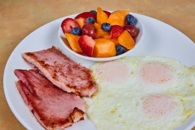 Fort Wayne, Indiana 'da klasik Amerikan kahvaltısı. Sunny-side yumurta, ızgara jambon ve canlı meyve karışımı..