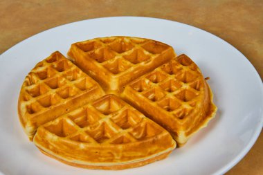 Beyaz seramik tabakta servis edilen altın kahverengi waffle, ev tarzı rahatlığı çağrıştırıyor ve Fort Wayne, Indiana 'da kahvaltı ya da brunch için mükemmel..