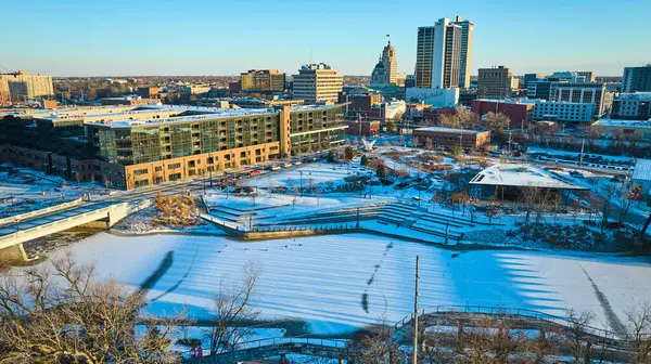 Winters afternoon glow over a bustling, snow-blanketed Fort Wayne, highlighting the blend of modern and historical architecture.