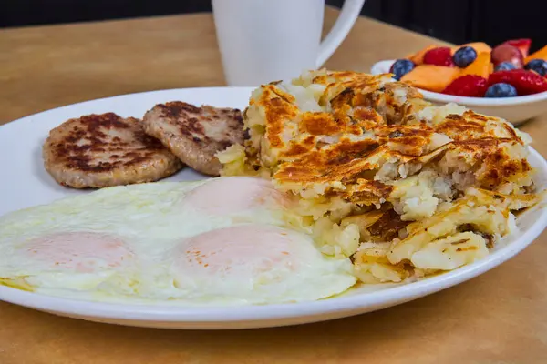 Inviting American breakfast in Fort Wayne, Indiana with sunny-side-up eggs, sausages, hash browns, and fresh fruit, perfect start to a vibrant morning.