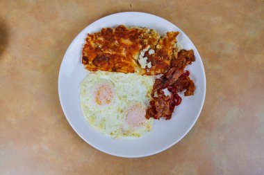 Fort Wayne, Indiana 'da rahatlatıcı bir sabah yemeği için mükemmel, beyaz bir tabakta sunulan, güneşli yumurta, kıtır domuz pastırması ve altın patates kızartmasından oluşan doyurucu Amerikan kahvaltısı..