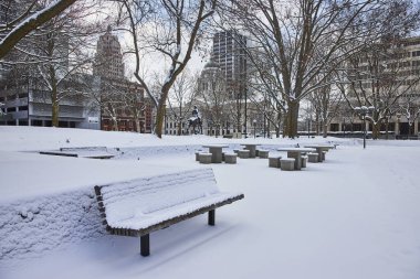 Snow-draped tranquility in Downtown Fort Wayne, Indiana - A serene snapshot of a wintry day at Freimann Square, with its iconic statue and snowy benches. clipart