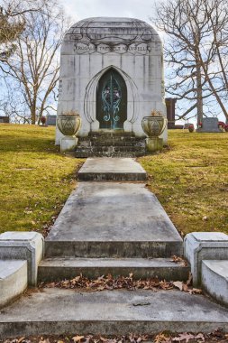 Daylight view of ornate mausoleum at Lindenwood Cemetery, Fort Wayne - a testament to remembrance and architectural grandeur amid autumnal peace. clipart