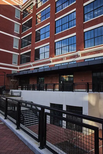 Electric Works modern architectural masterpiece in Fort Wayne, Indiana, showcasing a blend of old and new with red bricks and reflective glass windows against a clear sky.