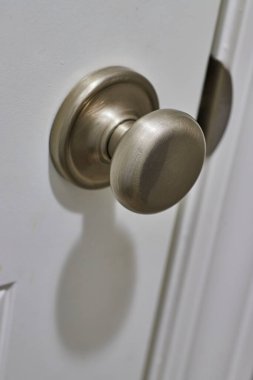Close-up of a modern brushed nickel door knob on a white door, displaying a minimalist design, shot in Fort Wayne, Indiana clipart