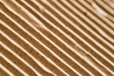 Bükülmüş karton dokusunun makro perspektifi, çok yönlü, geri dönüşümlü arka plan için doğal kahverengi renkleri ve ritmik çıkıntıları vurguluyor.