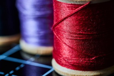 Geleneksel dikiş atölyesinde canlı kırmızı ve mor iplik makaralarının yakın çekimi, Fort Wayne, Indiana 'da sanatçılık somutlaştırma.