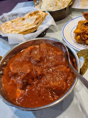 Geleneksel Hint ziyafeti Fort Wayne restoranında mavi bir masa örtüsü üzerinde köri, naan ve pakoras..