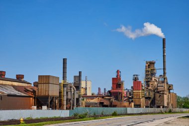 Varşova, Indiana 'da canlı gökyüzünün altında endüstriyel enerji santrali tüten bacaları ve canlı mavi arkaplanı olan geniş bir fabrika..